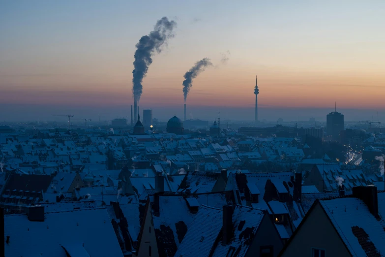 smokestacks are seen as the sun rises in a city