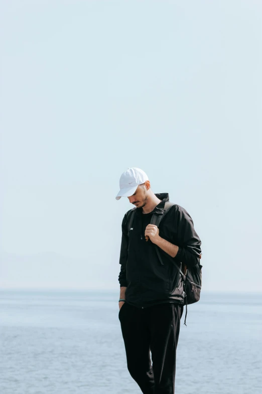 a man is standing on the beach looking down