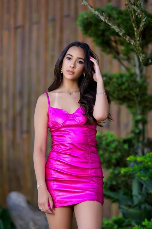 a young woman posing in a bright pink dress