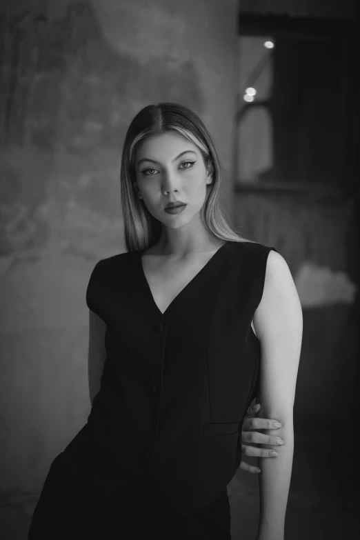 a woman poses in a black dress in a dark room