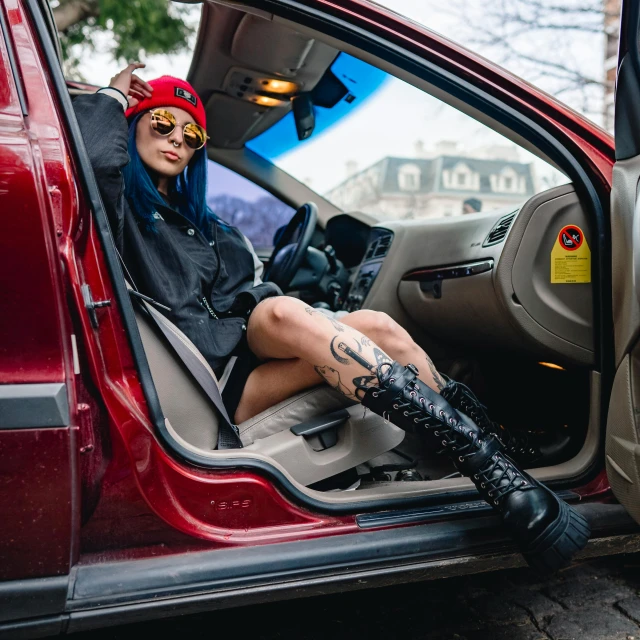 woman in motorcycle helmet and boots is sitting inside a car