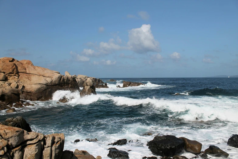 water splashes over rocks next to a beach