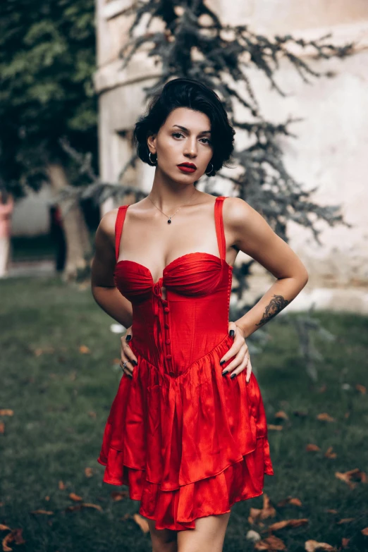 a woman in a red dress poses in front of trees