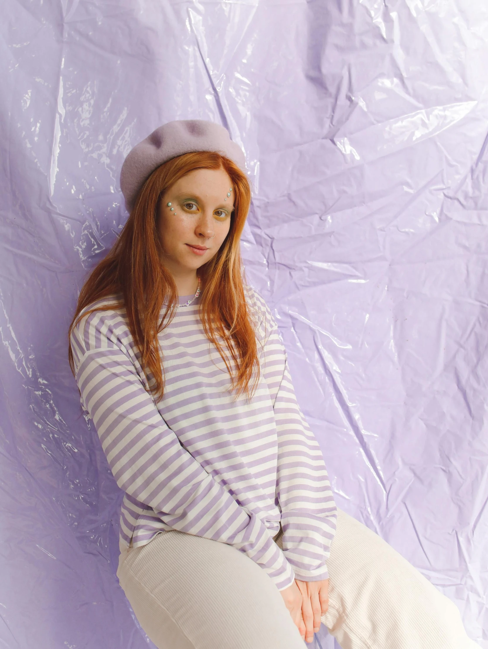 a girl in a striped sweater with a cap is laying on the ground