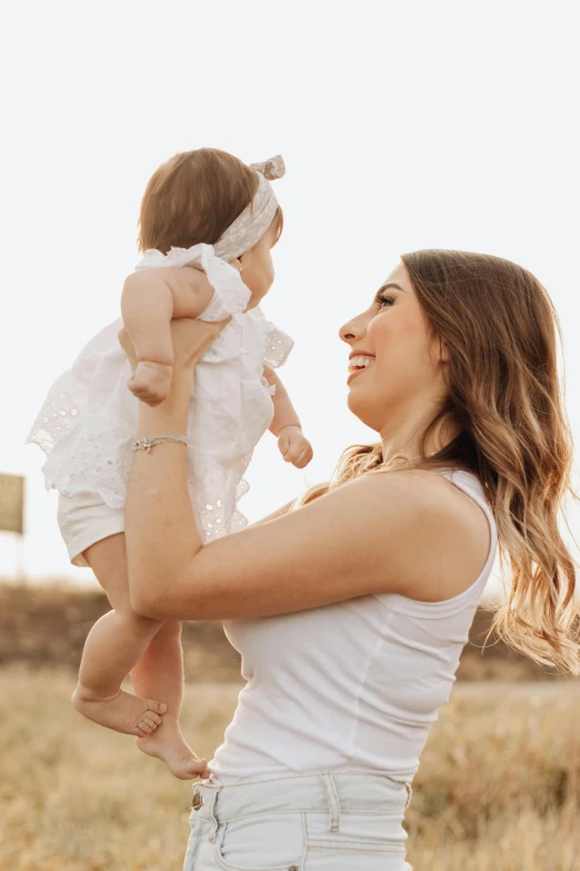 a woman holding up her baby in a field