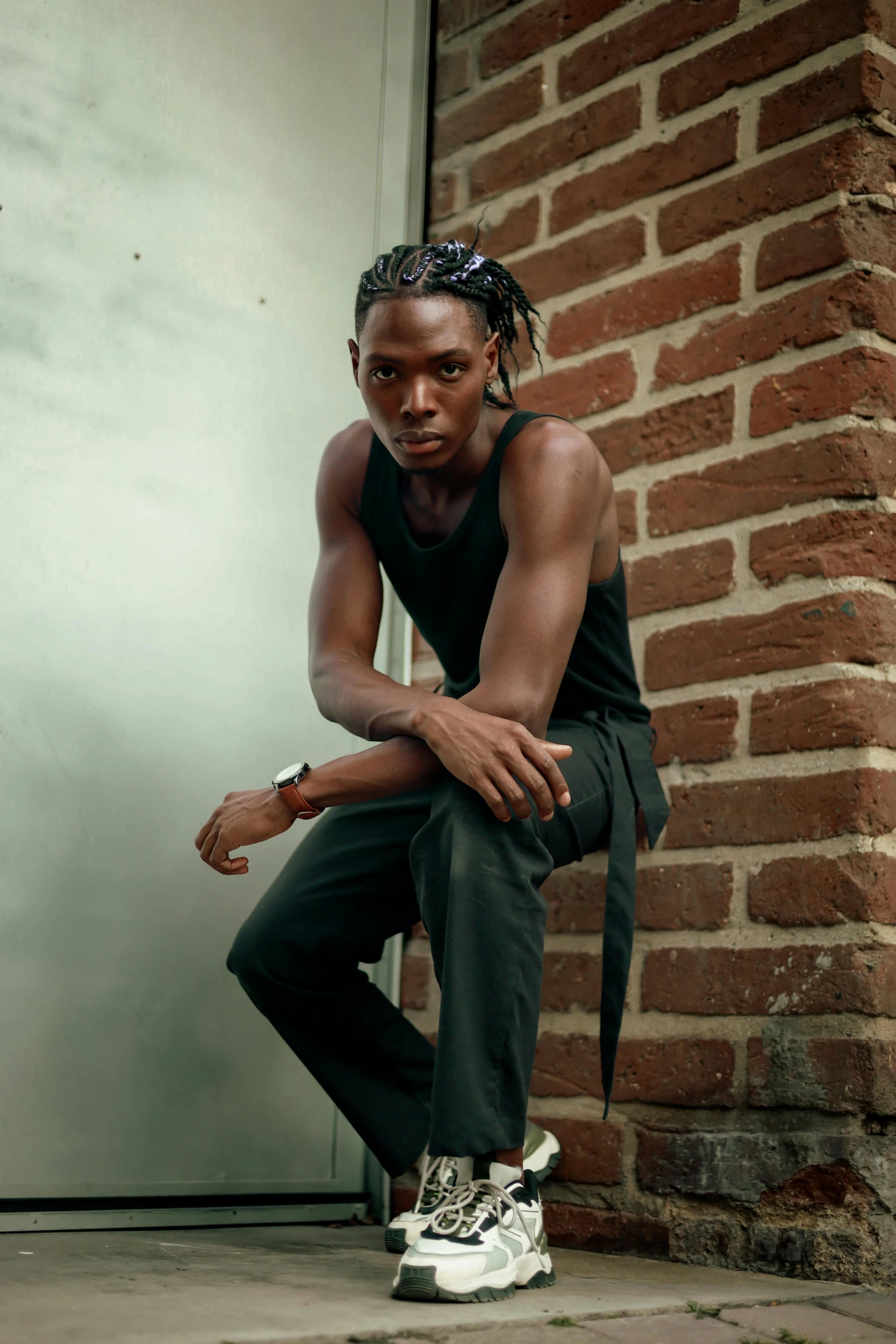 an african man leaning against a brick wall