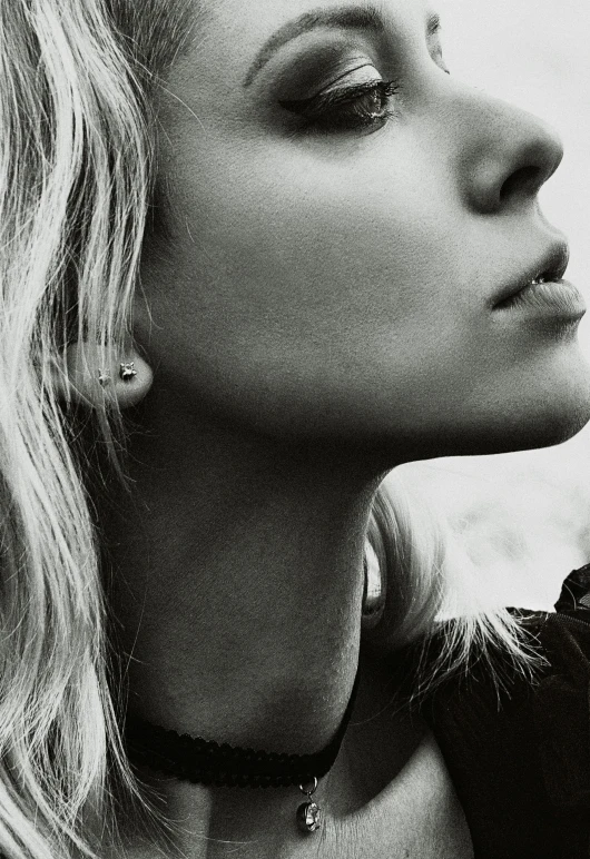 a beautiful young blond woman leaning on the side of a wall