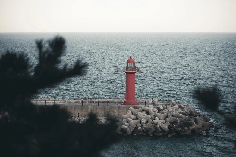 a light house near the ocean looking down on rocks