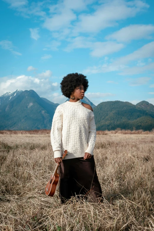 a woman stands alone in a field looking back