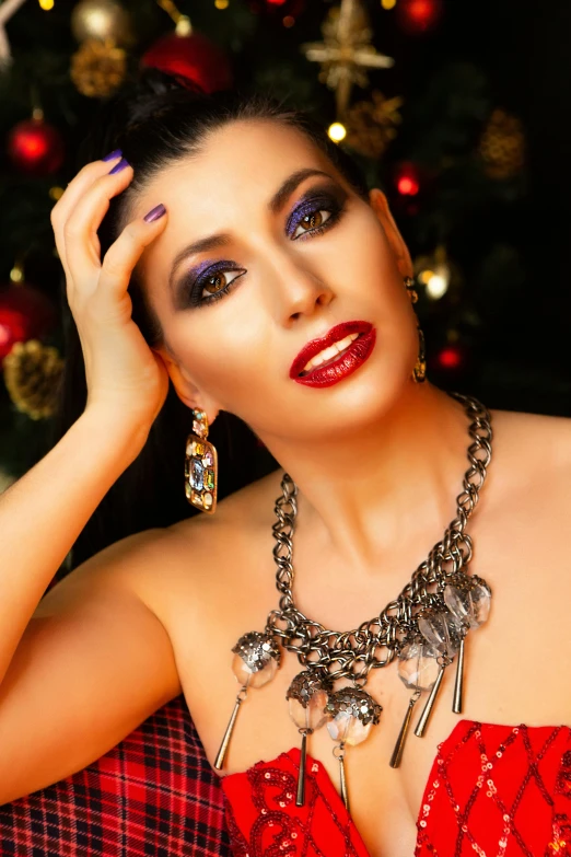 a woman wearing jewelry stands in front of a christmas tree