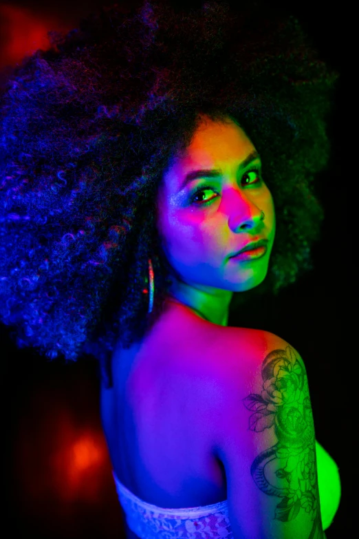 woman with a large afro in a pink, green and blue glow