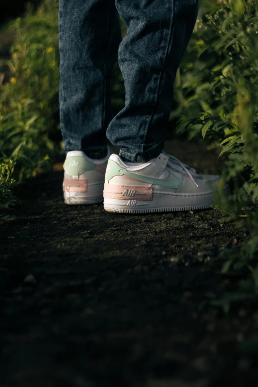 a person standing in some bushes wearing white sneakers