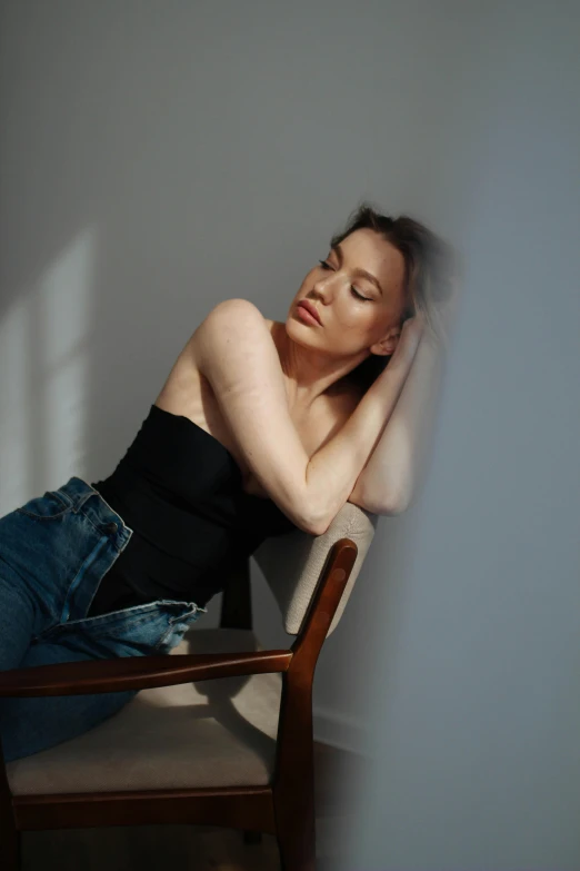 a woman leaning against a wall with her head on the chair