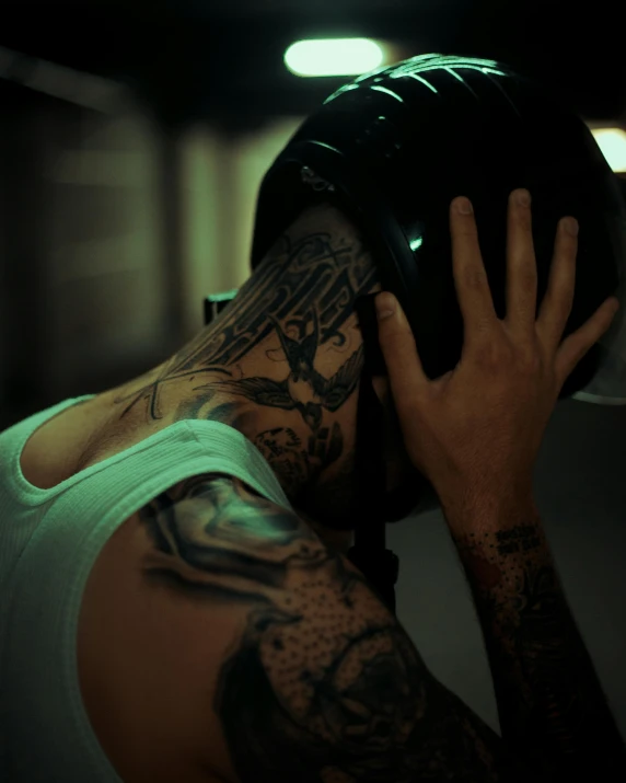 tattooed man with large black helmet covering his eyes