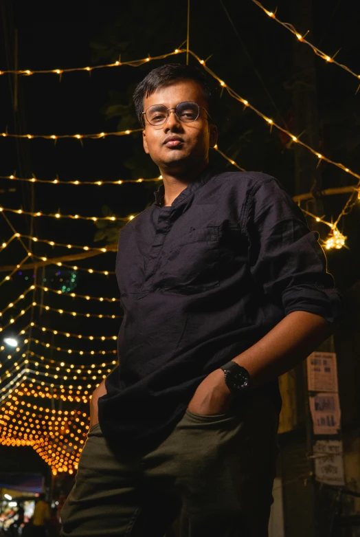a man with glasses standing in front of some lights