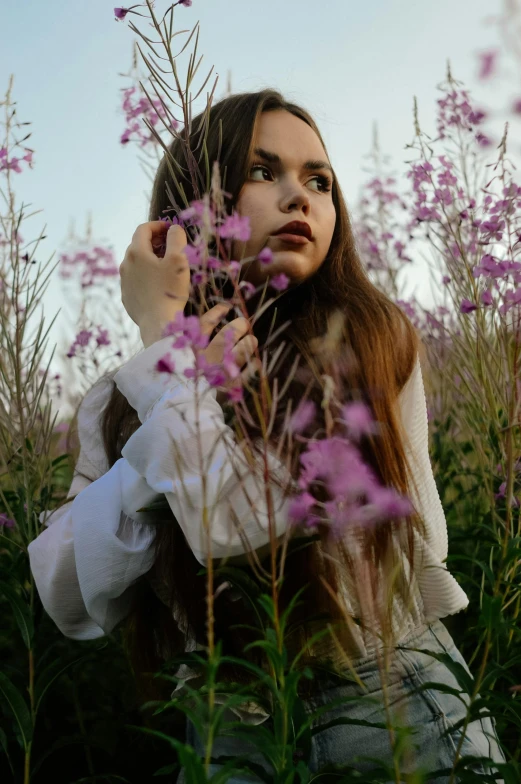 a woman sits on the ground in a field with flowers