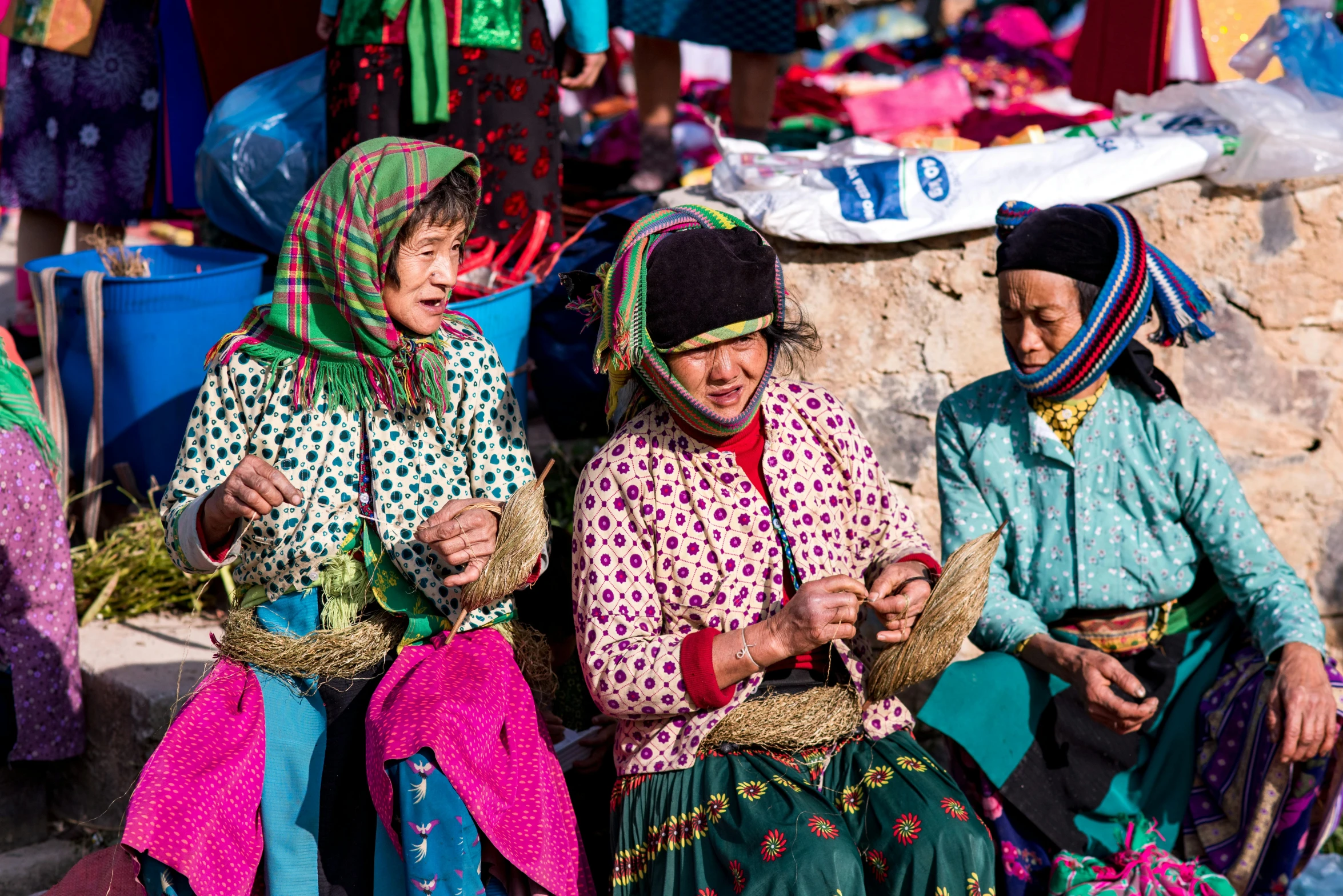 three women in colorful clothing sitting on some steps