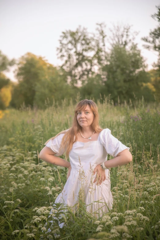 an elegant woman in a white dress poses in the tall grass