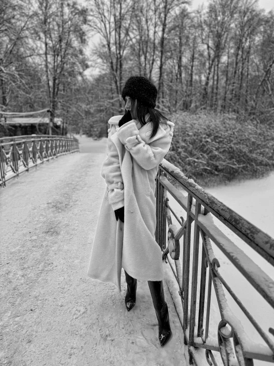 a woman standing in front of a fence looking at trees