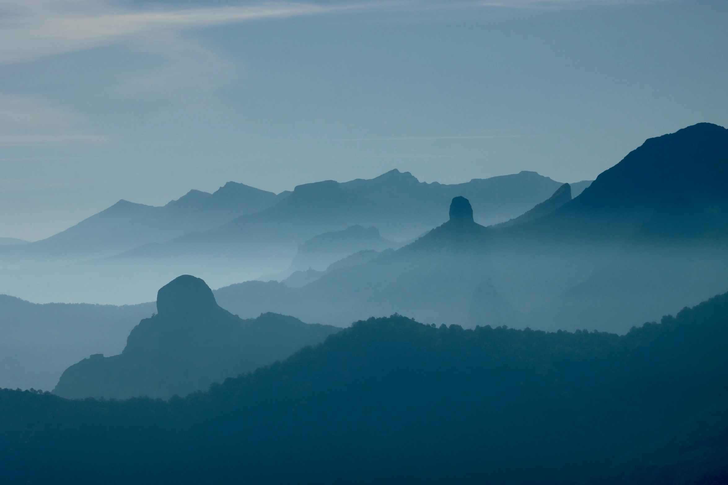 a black and white image of mountains covered in fog