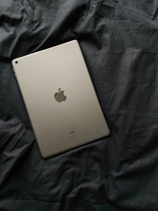 an apple ipad is laying on top of a bed