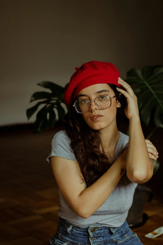 a woman in glasses and red beanie sitting down