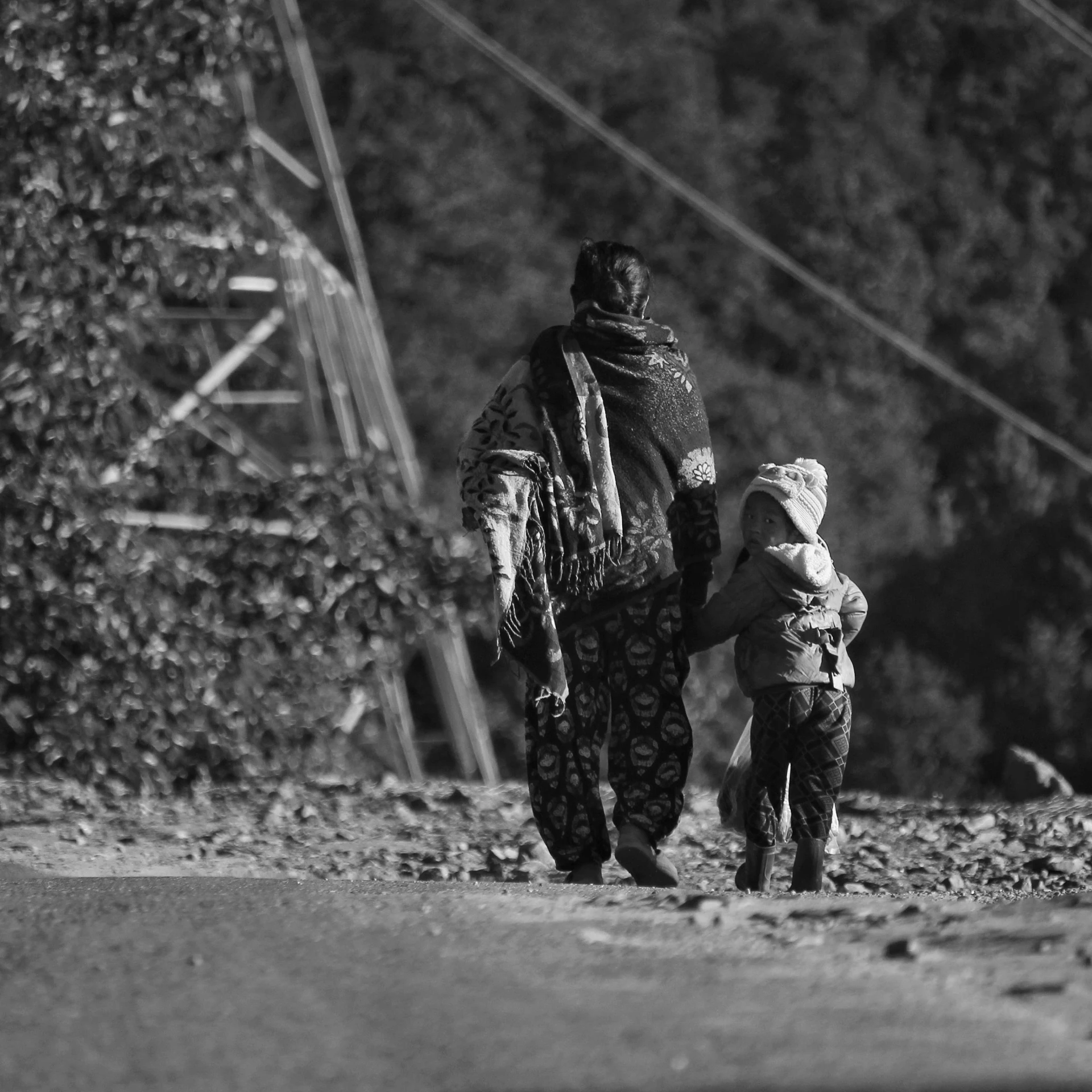 a woman walking next to a child on top of a forest