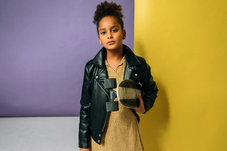 a young woman leaning against a wall holding a purse