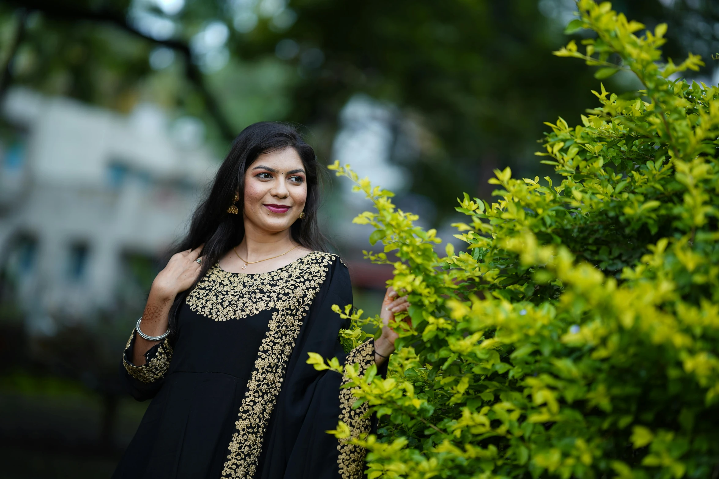 woman standing next to bushes outside in front of a house