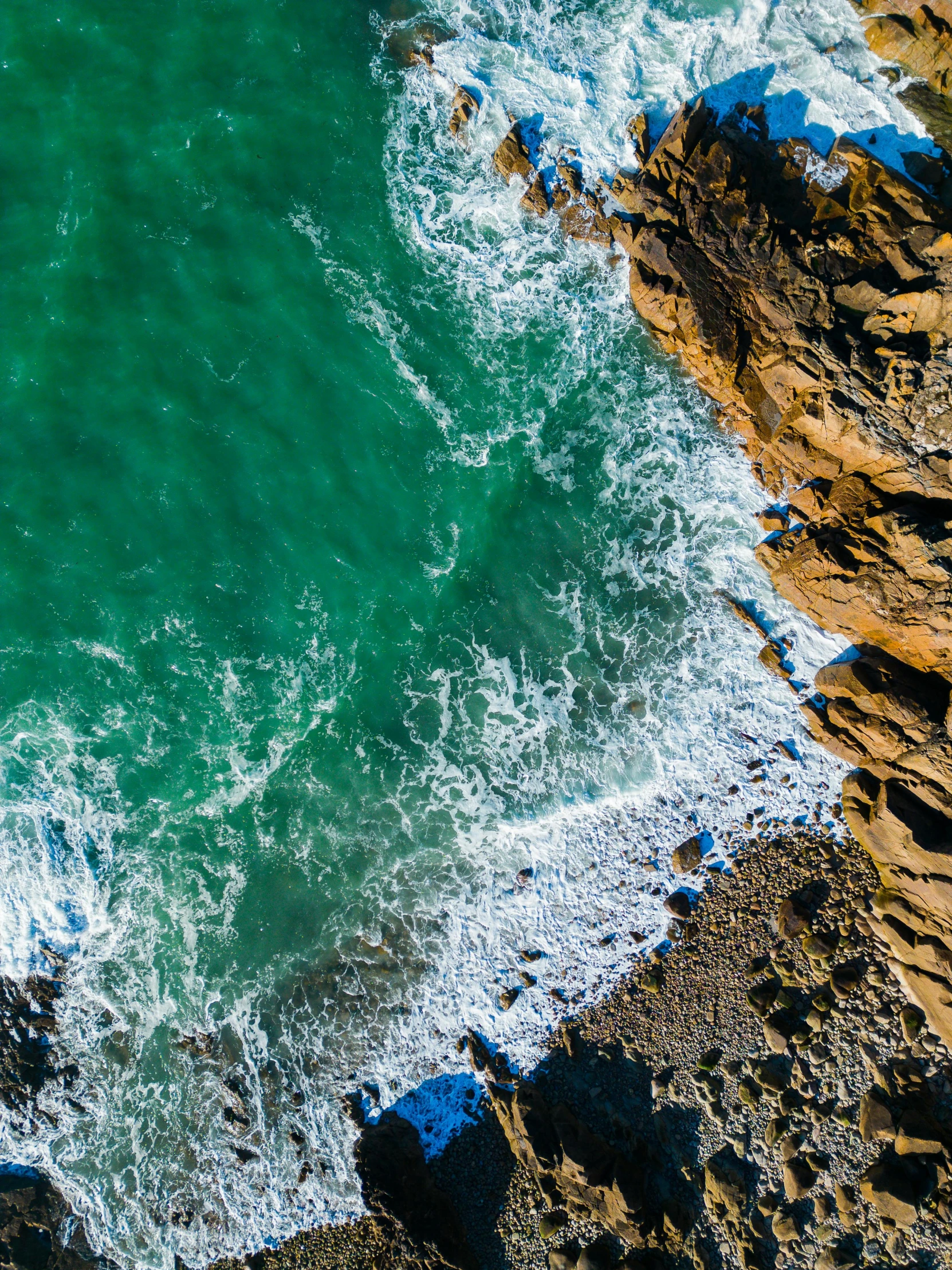 a rock cliff overlooks an ocean body of water