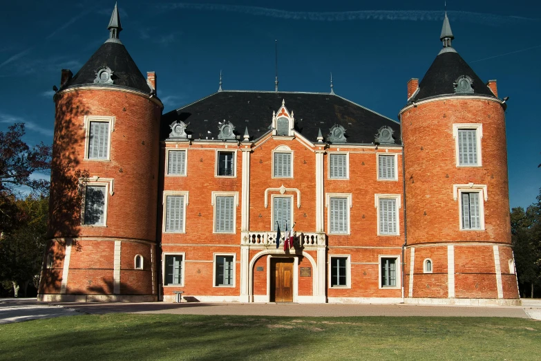 an old brick building with tall towers and a large yard