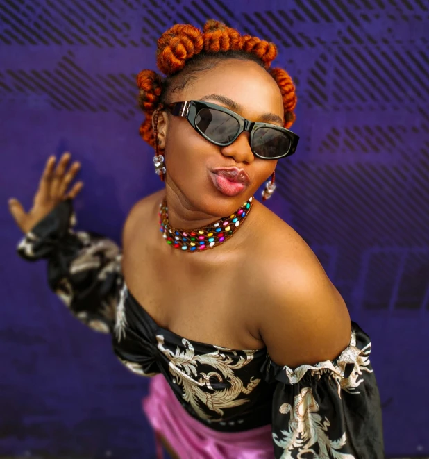 an african american woman in a purple outfit and bright head wrap