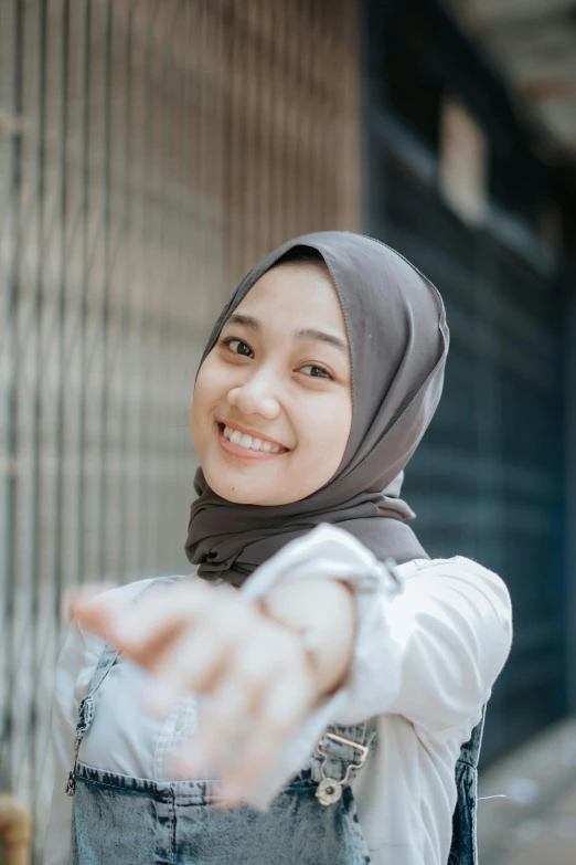 smiling woman wearing a hijab, pointing out her hand