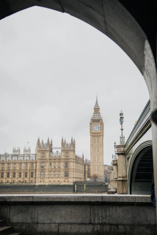 a clock tower behind a bridge on a rainy day