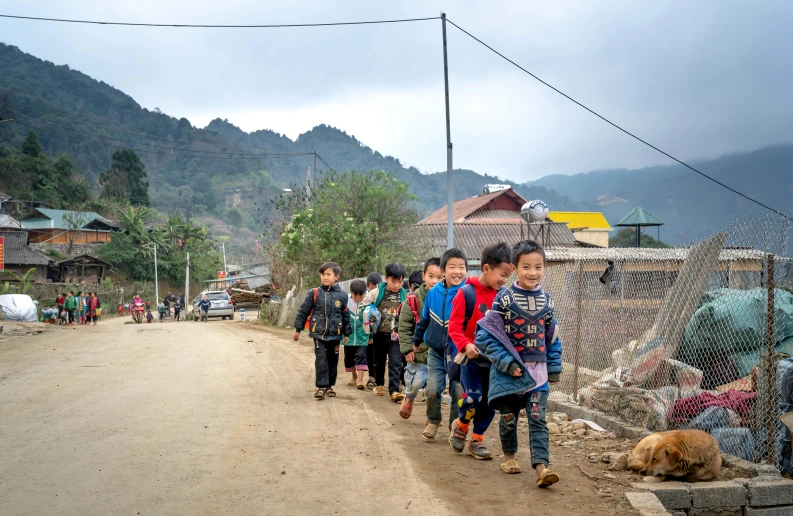 a group of children walking down the street in front of houses