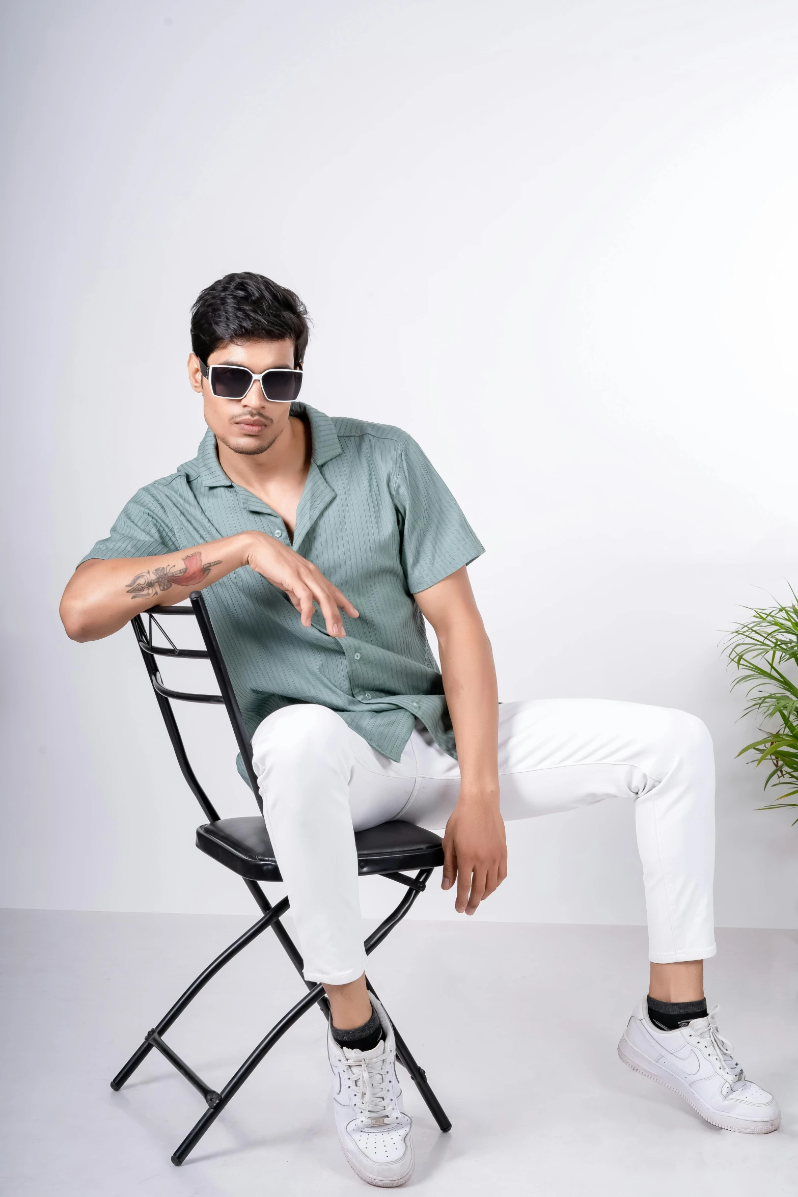 the man wearing sunglasses and a green shirt is sitting in a chair