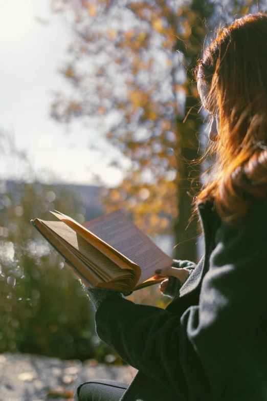 a woman reading a book in a park