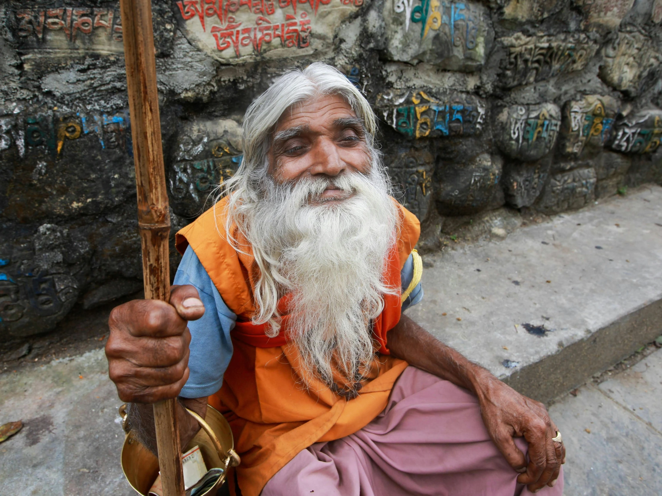 an old man is sitting on the ground holding a stick