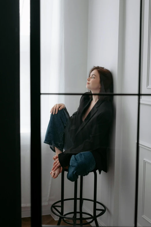 a woman sits on top of a stool near a wall