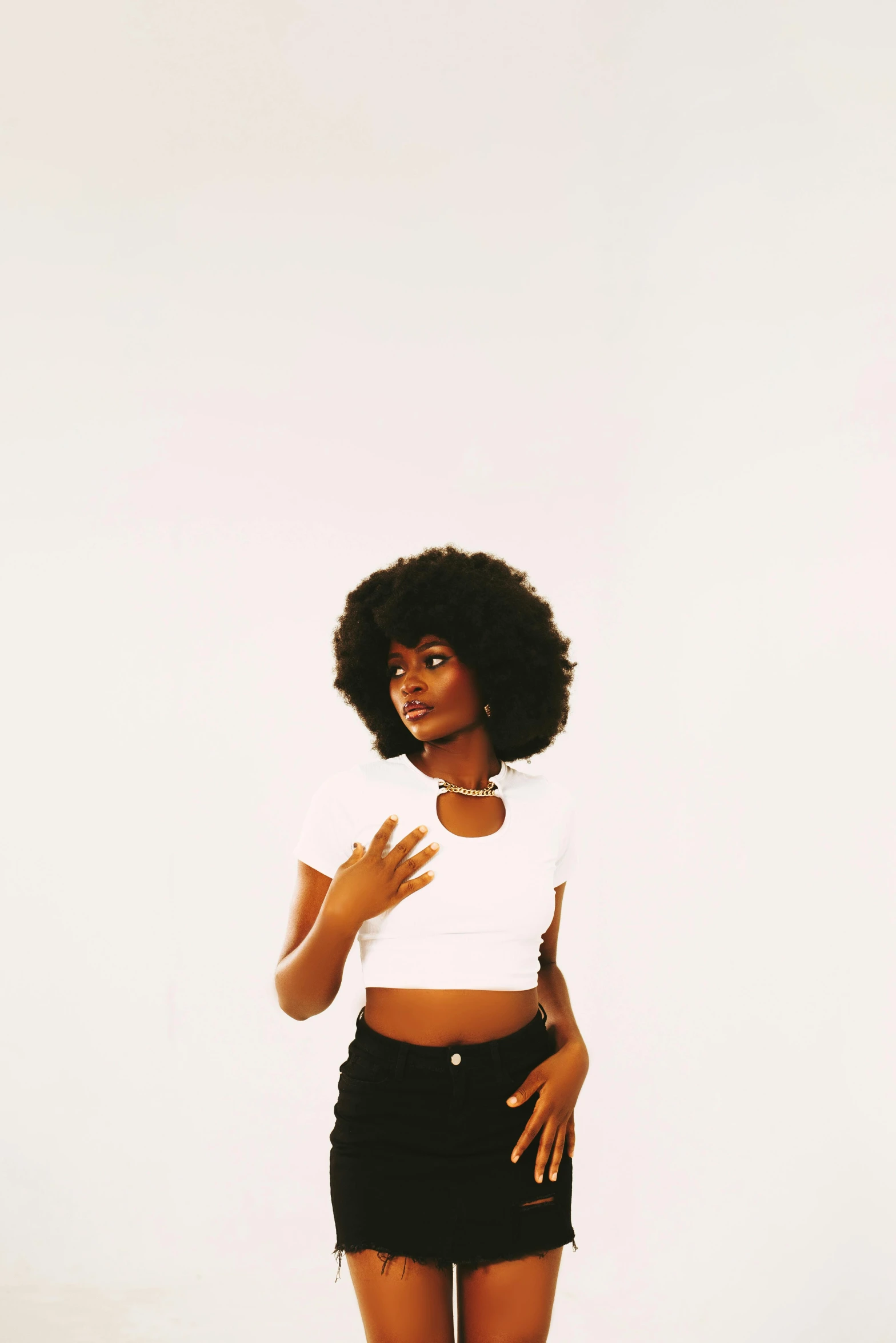 woman with afro in a white crop top posing with a skateboard