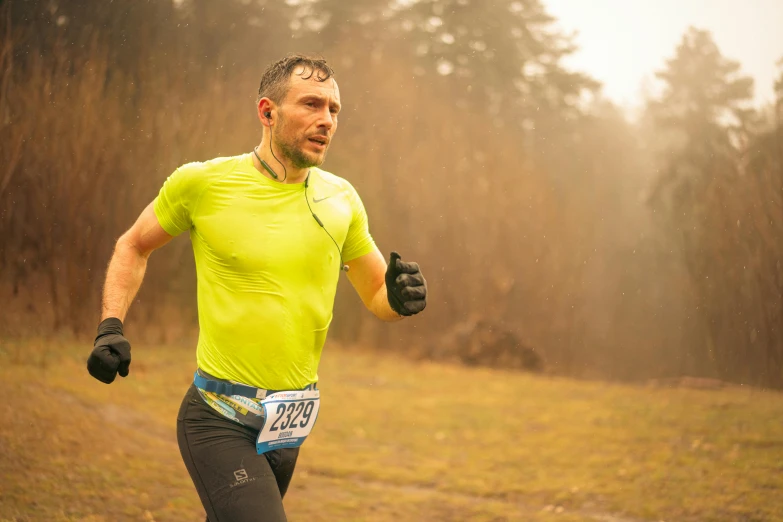 the runner in a yellow top and black pants runs through a forest