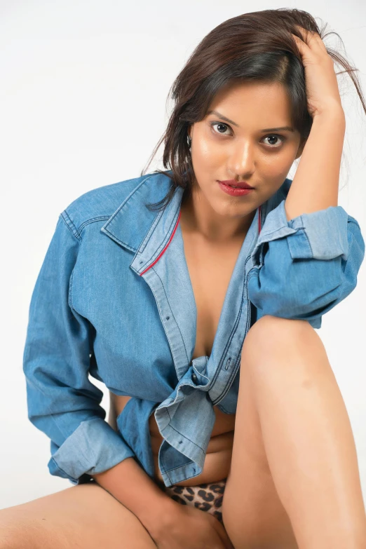 woman in jean shirt sitting on her stomach and posing