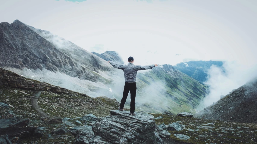 the man stands on the top of a mountain