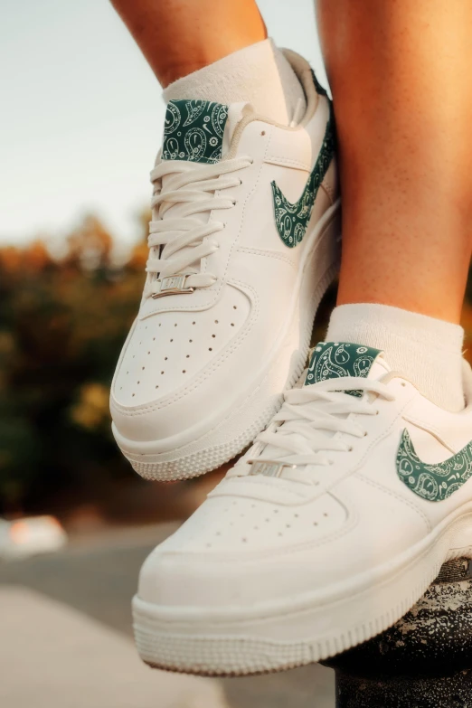 a person's feet with green print on the laces of tennis shoes