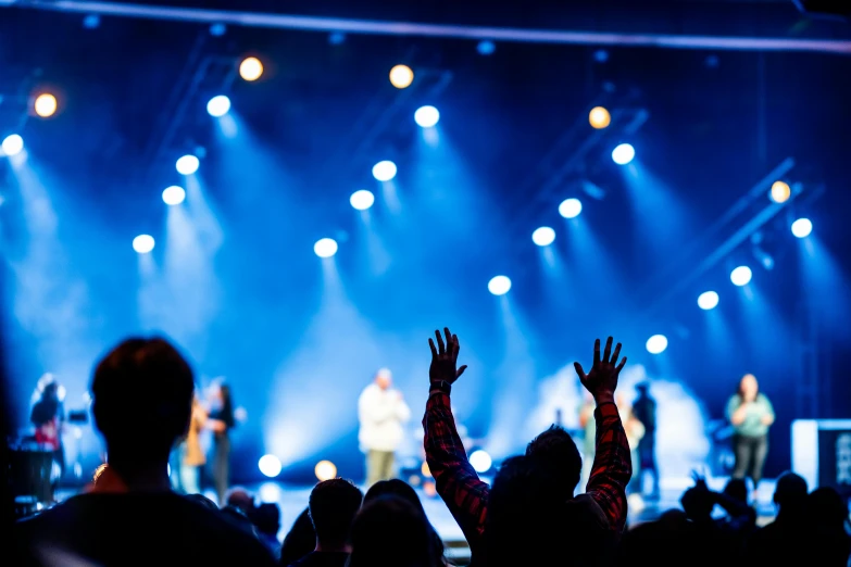 a man raising his hands as someone else stands on stage