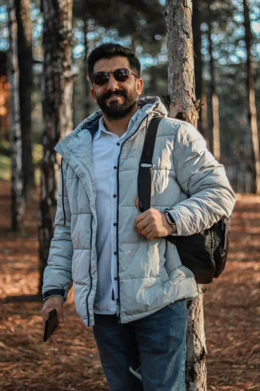 a man wearing sunglasses while walking next to a tree