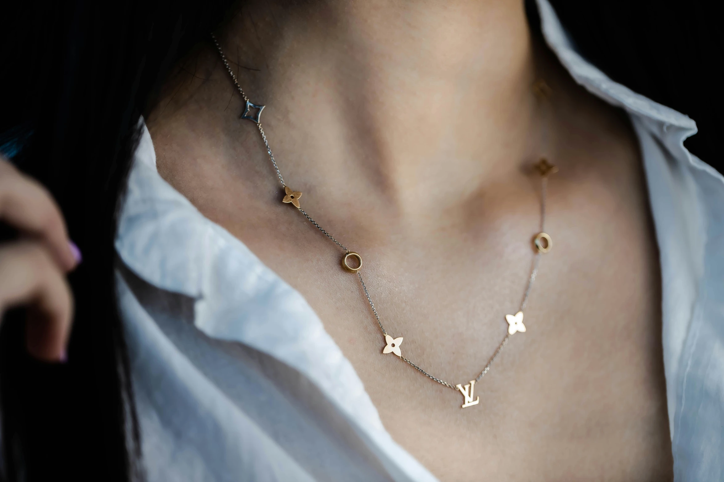 a woman wearing a necklace with three letters in the shape of stars