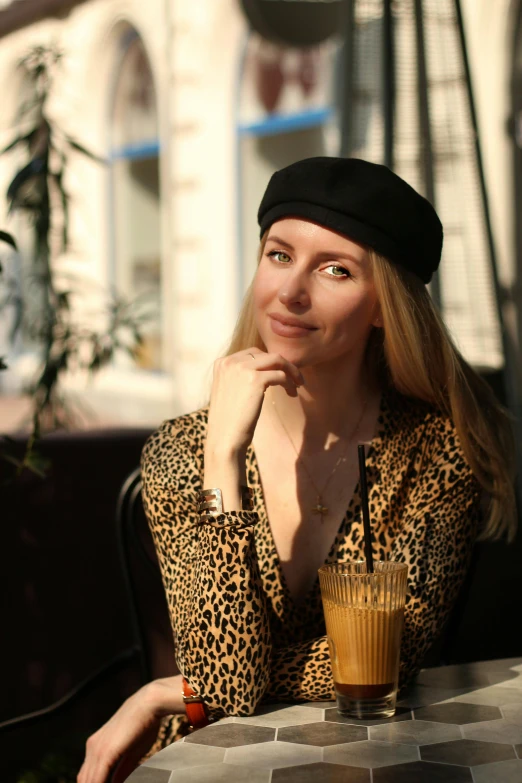 a woman sits at a table wearing a hat