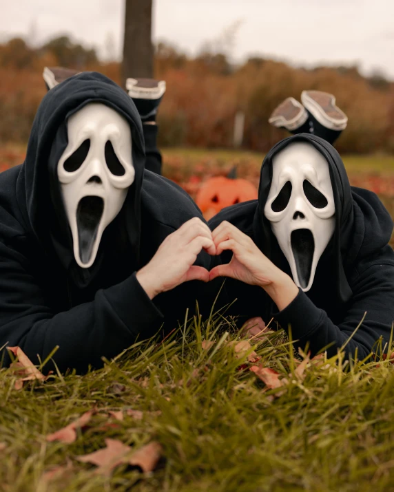 two people dressed up in ghost masks on the ground