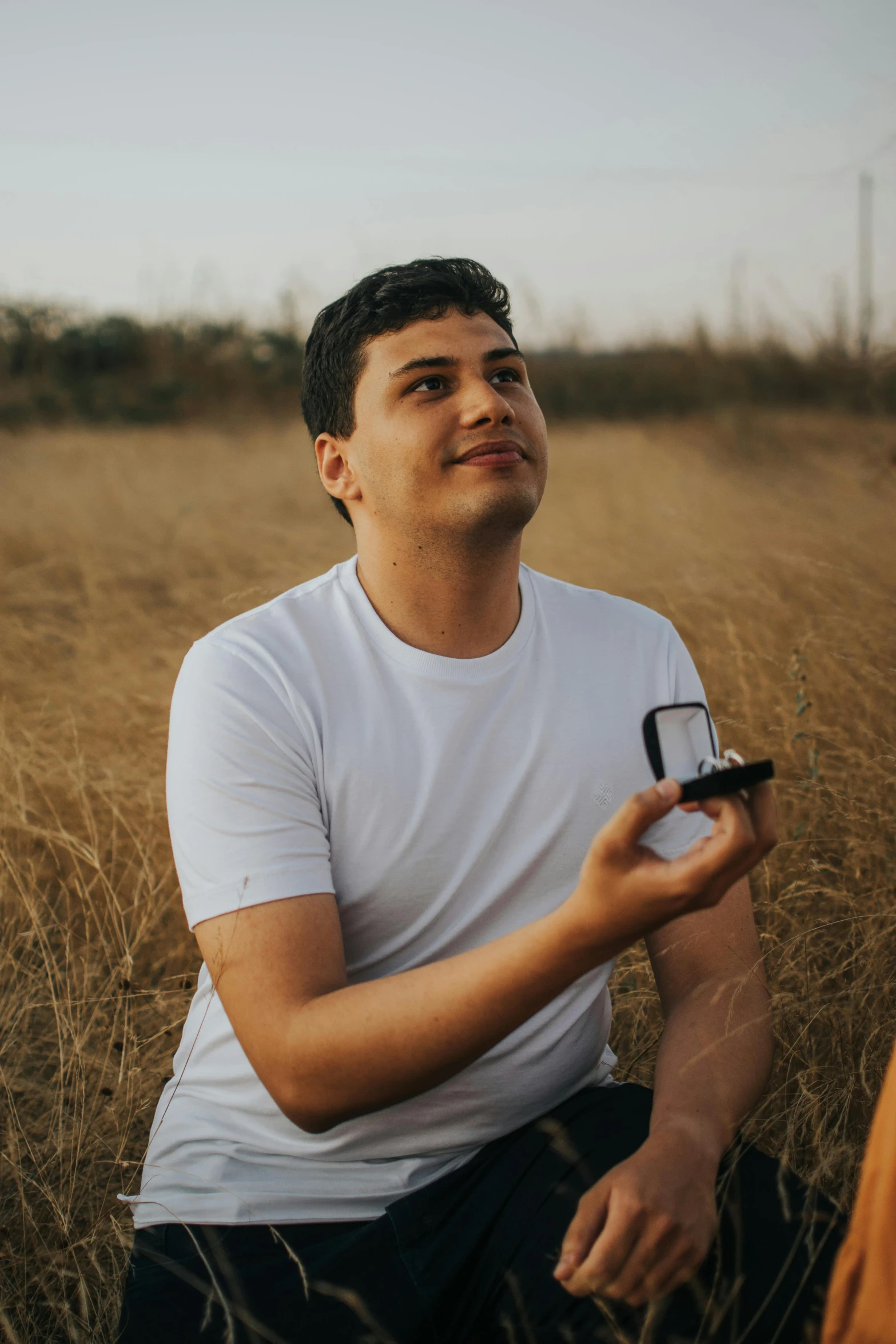 a young man in a field holding soing with his hand